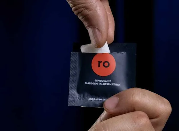 Man holding Benzocaine wipe with Roman swipe packet