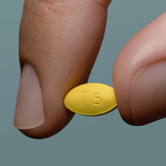 a generic of Cialis pill held between two fingers