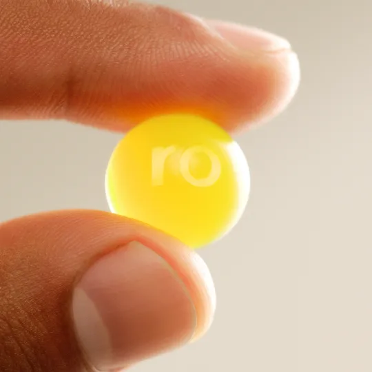 a Ro Daily Rise Gummy held between two fingers