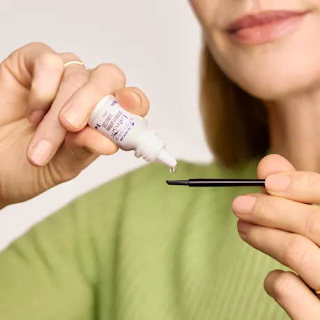 woman adding a drop of Latisse on the brush