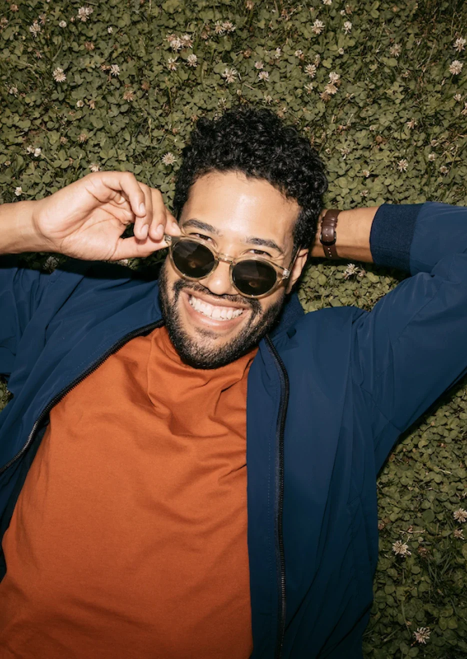 Man relaxing in the grass with sunglasses looking fly.