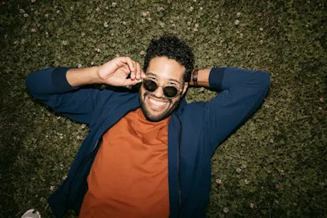 Man relaxing in the grass with sunglasses looking fly.