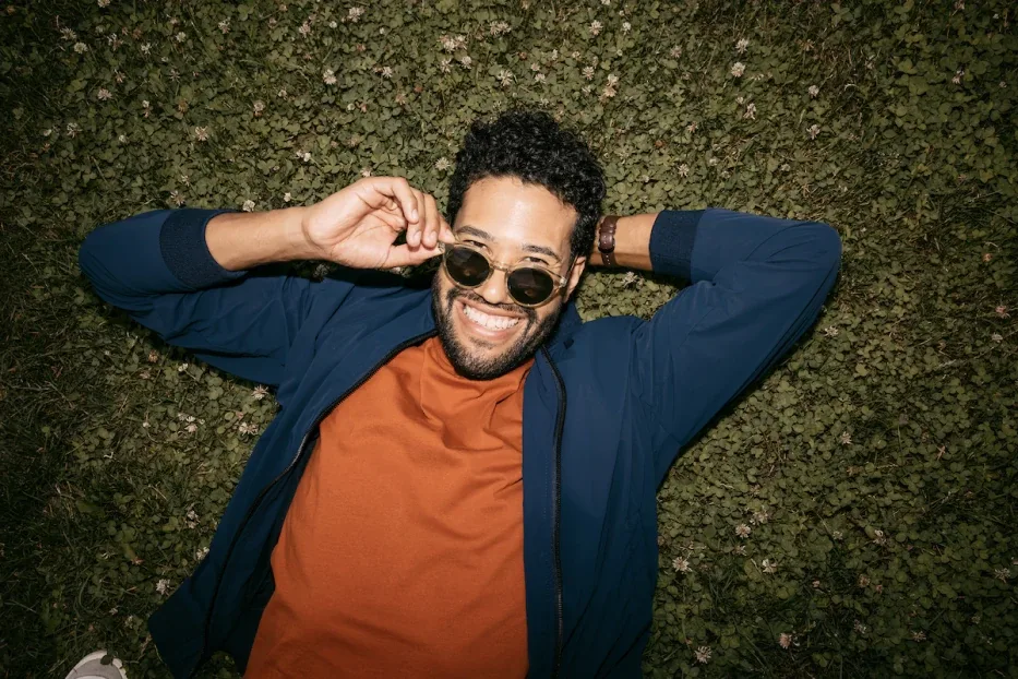 Man relaxing in the grass with sunglasses looking fly.